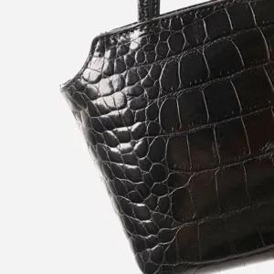Detailed view of a black crocodile embossed genuine leather handbag, elegant and stylish.