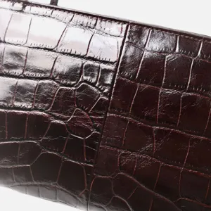Brown crocodile embossed leather handbag detail, premium cowhide underarm bag close up.