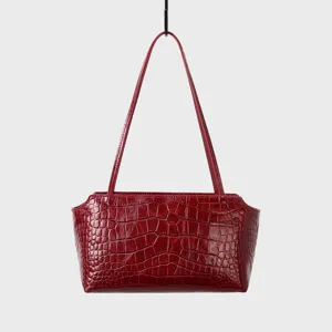 Red crocodile pattern leather detail of shoulder bag, luxury underarm handbag texture.