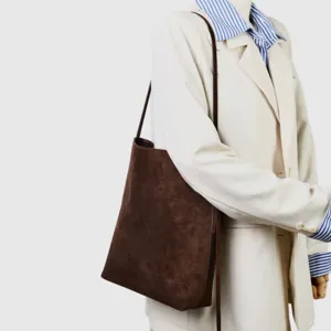 Primo piano della borsa tote minimalista in pelle scamosciata marrone scuro sulla spalla.