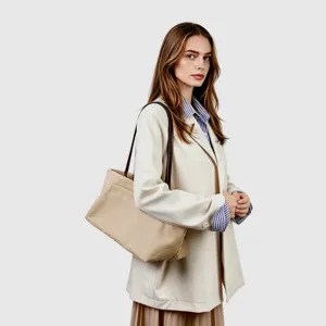 Vista detallada del bolso tote de lona, estilo hobo informal bajo el brazo con asa de cuero.