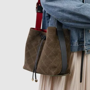 Detalle del bolso tipo saco de ante acolchado con cierre de cordón y asas dobles.