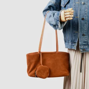 Vista detallada del bolso tote hobo de ante marrón con mini monedero en exhibición de maniquí.