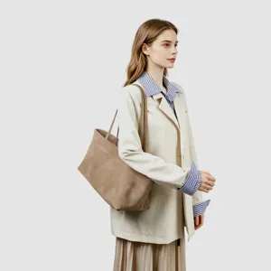 Vista detallada del bolso tote de ante marrón llevado por una modelo en estudio.