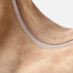 Primer plano detalle de bolso de ante marron con cremallera metalica y costuras.