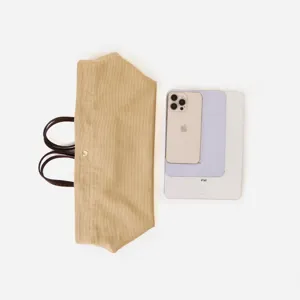 Vista detallada del bolso tote de lona con comparación de tamaño junto al teléfono y tableta.