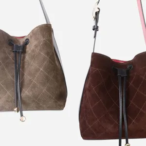 Vista de cerca detallada de bolsos cubo de ante acolchados con cordones de cuero.