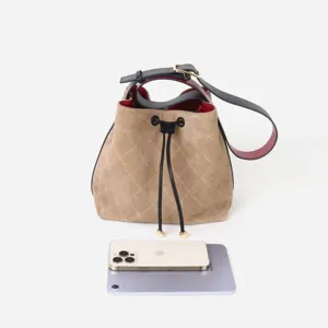 Vista detallada del bolso tipo cubo de ante acolchado con cordón para referencia de tamaño.