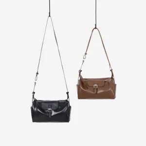 Vista detallada del bolso de hombro de cuero para mujer con hebilla de metal y cremallera.