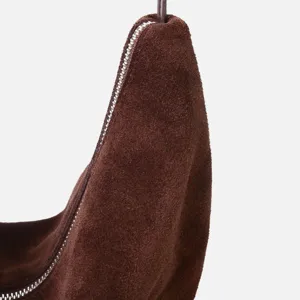 Primer plano detallado del bolso hobo de ante marrón en forma de media luna fina.