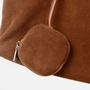 Detalle del bolso de ante marrón con mini monedero adjunto y cremallera de metal suave y elegante.