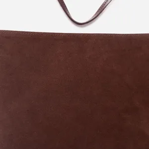 Primo piano dettaglio borsa in pelle scamosciata marrone scuro, texture fine e cuciture.