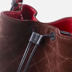 Bolso bombonera acolchado de ante marrón con cierre de cordón y forro interior de cuero rojo.