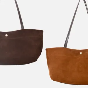 Primer plano detalle de bolso tote de ante marrón con tirantes finos y botón a presión.