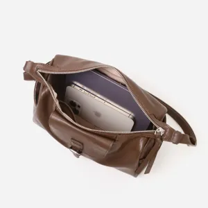 Detalle del bolso de cuero marrón que muestra la amplia capacidad interior y textura fina.