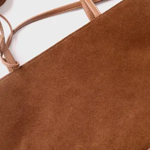 Detalle de bolso tote de ante marrón, bolso de hombro hobo minimalista de mujer con correa.