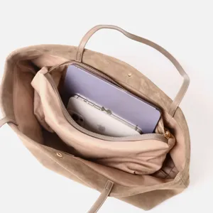 Detalle interior del bolso tote de ante marrón con gran espacio y compartimento con cremallera.