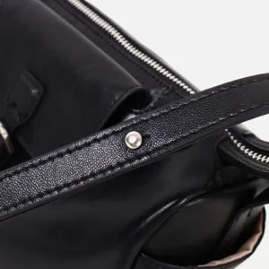 Primer plano detallado de bolso de cuero negro con textura fina y costuras precisas.