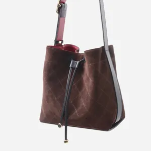 Bolso saco acolchado de ante marrón con correa de cuero negro y cierre de cordón.