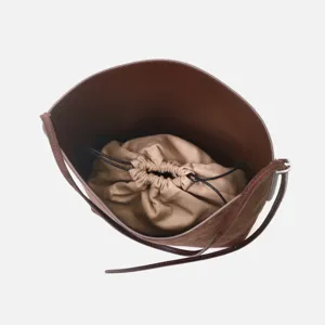 Borsa a secchiello in camoscio marrone con sacchetto interno con coulisse beige e tracolla.