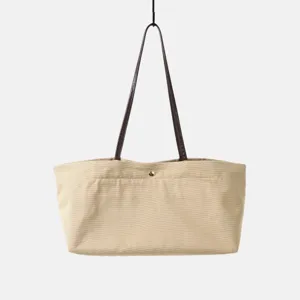 Bolso tote de lona beige con asas de cuero marrón y botón de presión dorado para mujer.
