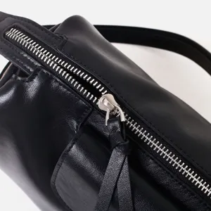 Detalle de bolso de cuero negro, cremallera metálica premium y tirador de piel vacuna.