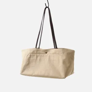 Detalle de bolso tote de lona y cuero, con material duradero y botón a presión.