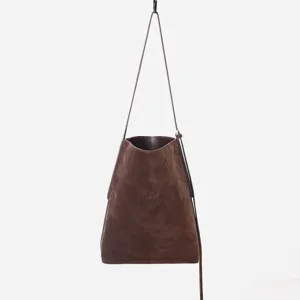 Primo piano della borsa a secchiello in camoscio marrone scuro che mostra consistenza e tracolla.
