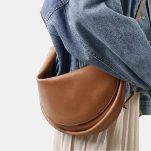 Sac demi-lune en cuir marron, sac porté épaule minimaliste style croissant détail.