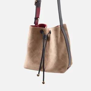 Bolso cubo acolchado de ante con cierre de cordón ajustable y correa de hombro en contraste.