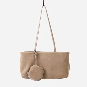 Detalle cercano del elegante bolso de hombro hobo de ante colgando con un pequeño monedero.