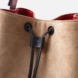 Bolso estilo cubo acolchado de ante con vista detallada de cierre de cordón y forro rojo.