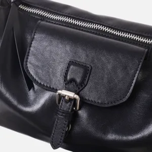 Primer plano detallado del bolso de hombro de cuero negro, textura suave y cremallera metálica.
