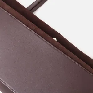 Bolso tote de piel marrón primer plano detalle mostrando textura lisa y forro de ante.