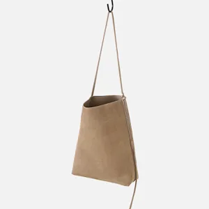 Vista dettagliata della borsa a secchiello minimalista in pelle opaca appesa per esposizione.