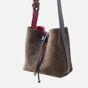 Elegante bolso de cubo acolchado de ante marrón con correa negra y forro rojo chic.