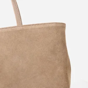 Detalle de bolso tote de ante marrón con textura suave y costuras finas y elegantes.