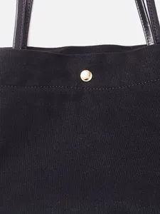 Bolso tote de lona negra con correas de cuero genuino y elegante botón de presión dorado mujer.