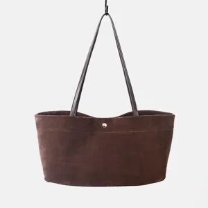 Vista detallada del bolso tote de ante marrón con textura fina y asas de cuero resistentes.