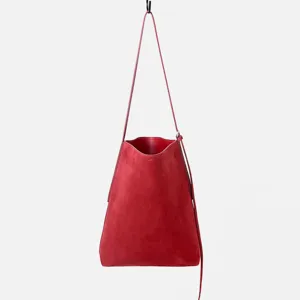 Dettaglio della borsa a secchiello in pelle scamosciata rossa con texture fine e tracolla.