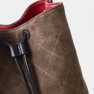 Detalle de la textura del bolso cubo acolchado de ante marrón con costuras elegantes.
