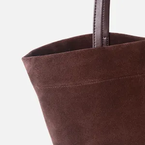 Detalle de bolso tote de ante marron, asa de bolso de mano de gran capacidad y textura.