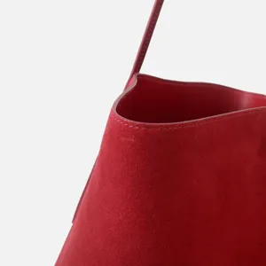 Dettaglio borsa a secchiello in camoscio rosso, elegante borsa a spalla per l'autunno.
