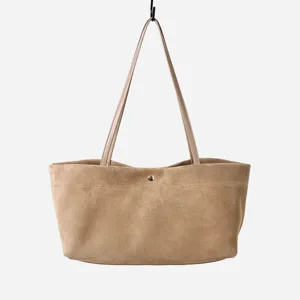Detalle del bolso tote minimalista de ante, con textura suave y finas correas para los hombros.