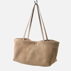 Primer plano detallado del bolso tote de ante caqui con asas finas y textura suave.