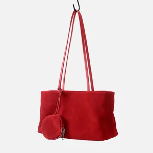 Detalle de bolso tote de ante rojo con textura de cuero suave y pequeño monedero redondo.