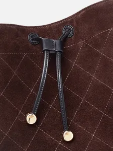 Bolso cubo acolchado de ante marrón con cordón de cuero de lujo y detalles metálicos elegantes.