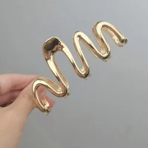 Nahaufnahme einer stilvollen goldenen Metall Wellen Haarklammer für elegante Frisuren.