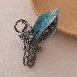 Gros plan détaillé de la grande pince à cheveux avec feuille brodée, strass et papillon.