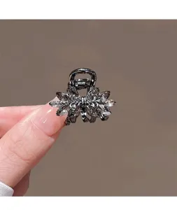 Gros plan sur une petite pince à cheveux en métal noir avec des cristaux sombres brillants.